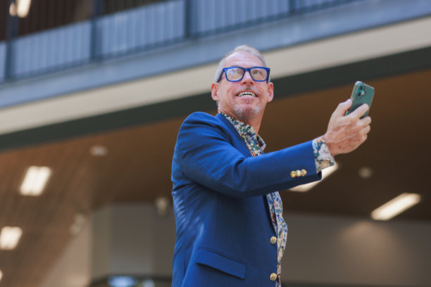 一位成熟的商界男士微笑着使用智能手机进行视频通话图片下载