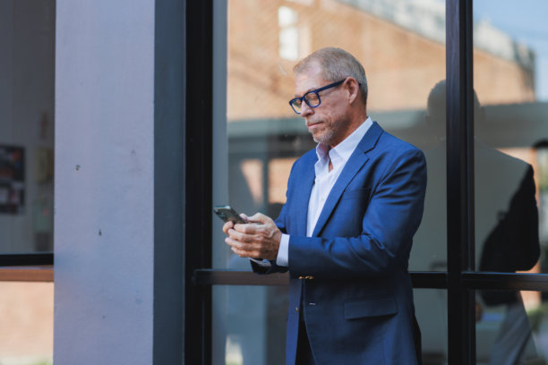 成熟男子在户外使用手机远程工作图片下载