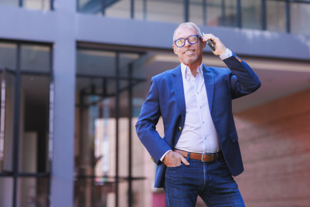 一位年长的商务人士在现代建筑外打电话图片下载