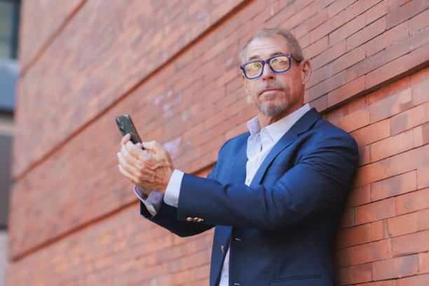 男人用智能手机靠着砖墙图片下载