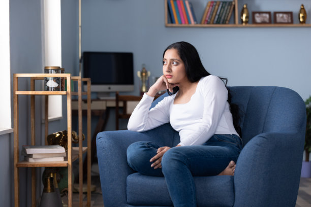一位穿着现代服装的美丽年轻女子在家中沙发上坐着的照片图片下载