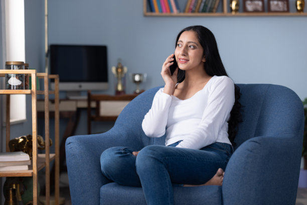 年轻女子坐在沙发上在家使用手机的图片图片下载