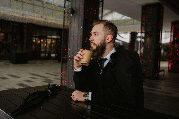 自信的商人在城市空间的一张桌子旁喝咖啡图片下载