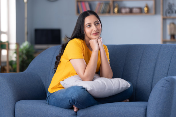 穿着休闲服的漂亮年轻女孩在家中沙发上坐着的照片图片下载