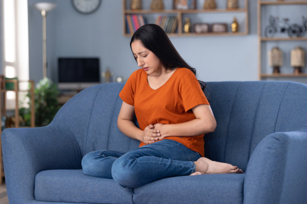 穿着休闲服的美丽年轻女孩在家坐在沙发上的照片图片下载