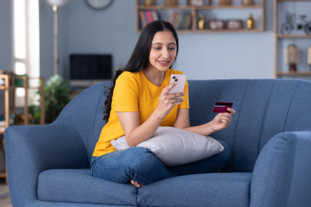 照片：一位美丽的年轻女子身穿休闲服在家里的沙发上购物图片下载