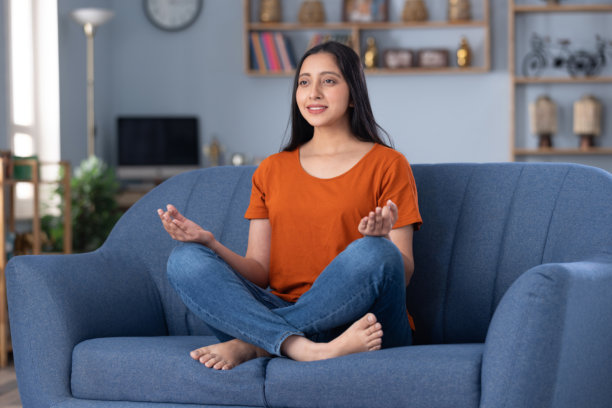 身着休闲服饰的美丽年轻女孩在家中沙发上坐着的照片素材图片下载