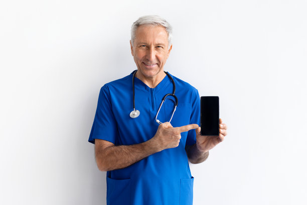 身穿蓝色医疗制服的年长男医生，手持带有空白屏幕的智能手机图片下载