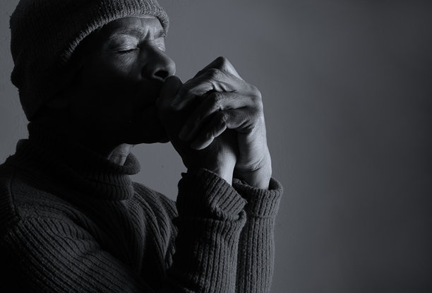 加勒比黑人男子在黑色背景前，手捧圣经祈祷，旁边有人物的照片图片下载