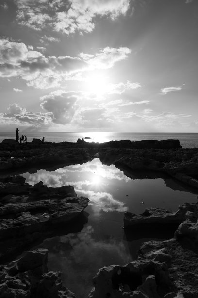 2025年12月29日，在马耳他萨利纳拍摄的黑白照片中，海岸盐沼中的静水在日落时分映照着天空，形成了抽象的形状和宁静的氛围。图片下载