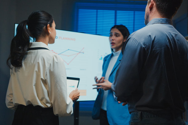 夜间办公室会议上，商业团队在大屏幕上展示业绩报告。团队合作、加班、沟通汇报、截止日期压力和专业决策的概念。图片下载