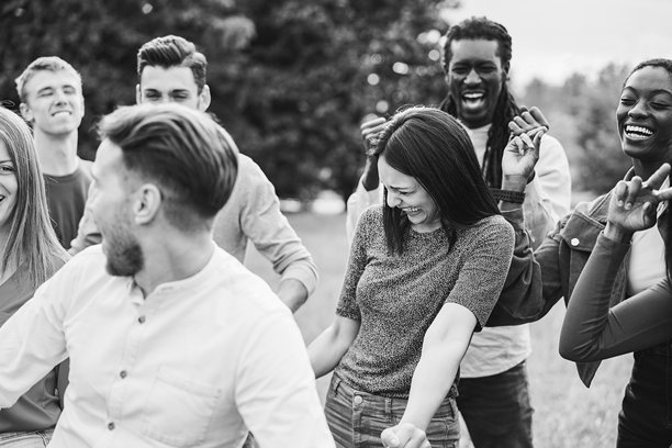 年轻多元化的年轻人在户外跳舞玩乐 - 生活方式、复古和节日概念 - 聚焦右侧非洲女孩的面部 - 黑白编辑图片下载