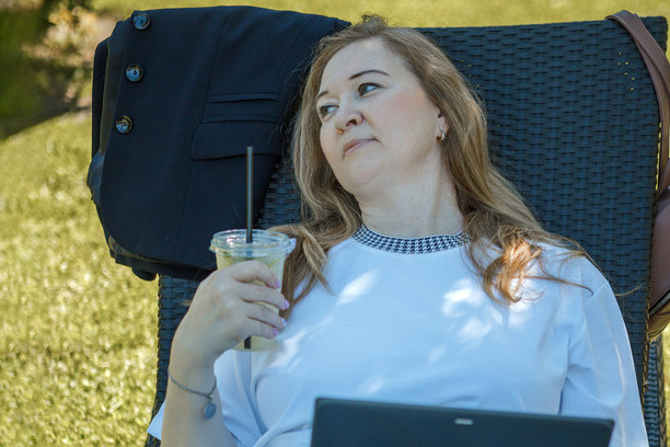 一位金发中年女性在花园的躺椅上用笔记本电脑工作，绿色居家办公概念。图片下载