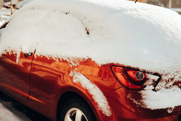 一辆鲜红色的汽车在大雪过后被厚厚的积雪覆盖。这张真实的图片捕捉了冬季出行和恶劣天气条件的挑战，非常适合故事叙述概念。图片下载