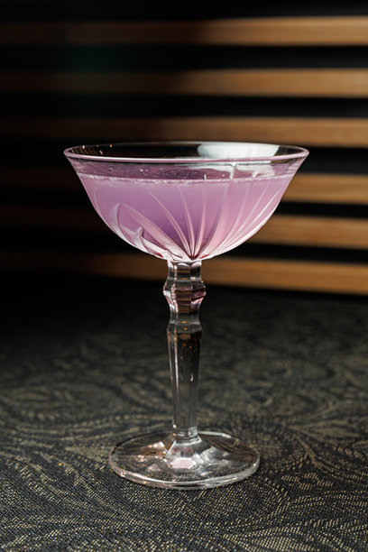 一款色彩鲜艳的鸡尾酒，盛放在复古玻璃杯中，置于现代酒吧的夜晚场景里图片下载