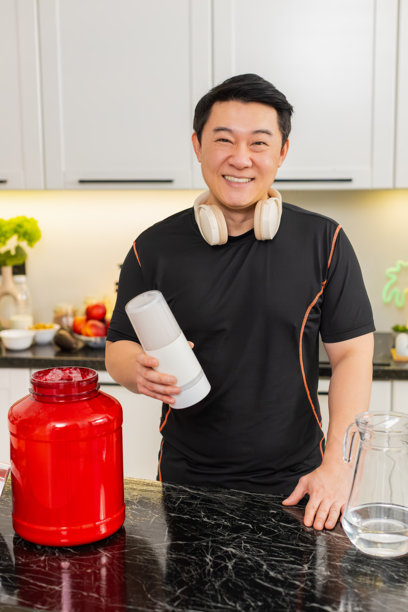 亚洲男性在剧烈运动后，在家里的厨房里等待着摇摇杯中混合的乳清蛋白粉饮品图片下载