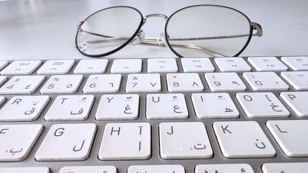 键盘镜头聚焦，照片突出眼镜与键盘的互动，特写镜头展示了在光洁的办公环境中眼镜和键盘的互动图片下载