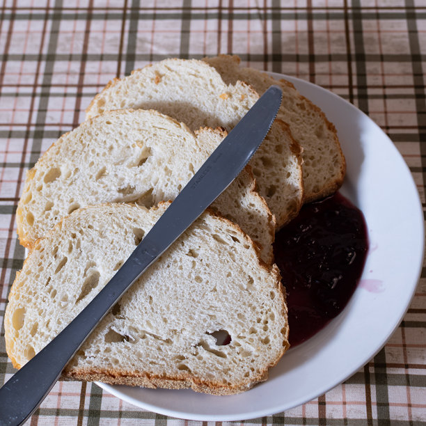 俯视视角下的面包和果酱。照片背景为格子图案，配有一把银色刀。图片下载