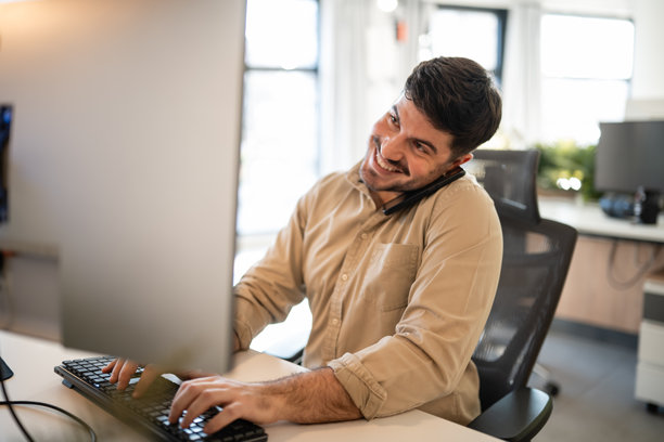 快乐的男人同时处理多项任务，一边打电话一边打字图片下载