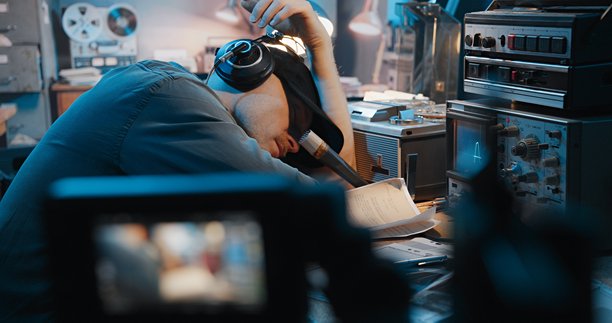 谍战或战争电影的幕后花絮。摄像机正在拍摄一名演员，他假装在一个复古收音机旁睡觉图片下载