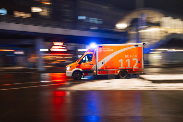 柏林消防紧急救护车，车身带有“Notruf 112”标识，在湿滑的柏林街道上行驶，消防员照片图片下载