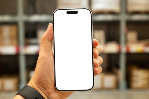 男人手持智能手机，屏幕为白色空白，背景是模糊的仓库，人工智能物流和库存管理概念。供应链物流、智能仓储和在线购物。图片下载