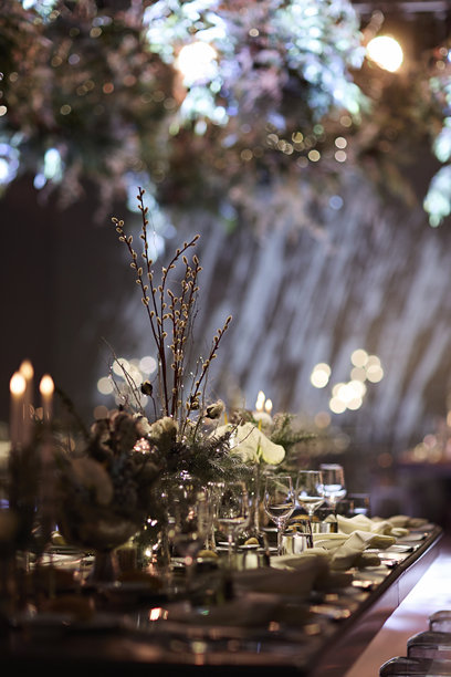 优雅的冬季餐桌布置，配有柔和灯光和节日散景背景。素材图片图片下载