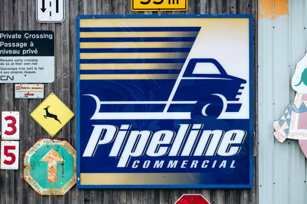 魁北克木墙上挂着的带有风格化卡车图案的复古管道商业广告牌图片下载