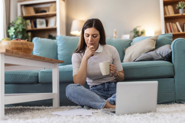 年轻女子坐在地板上使用笔记本电脑进行规划、创意构思、制定策略或审查网站的样机或肖像。她是一名充满动力、快乐的初创公司女员工，从事技术工作，进行网络社交或经营网络博客。图片下载