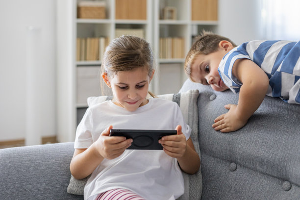 孩子们聚在一起坐在沙发上，看着智能手机屏幕图片下载