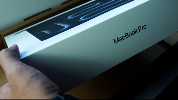 马来西亚，彭亨州 – 2026年1月8日 – 一双男人的手正在打开包装盒，展示里面太空黑色的 M5 苹果 MacBook Pro 14 英寸笔记本电脑。图片下载