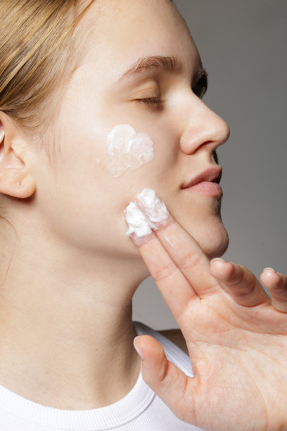 年轻女子在化妆品柜台前试用面霜图片下载