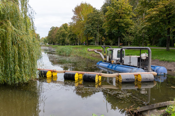 秋日阴天，重型机械在河道作业，清理障碍物并维持公共绿地内的水流图片下载