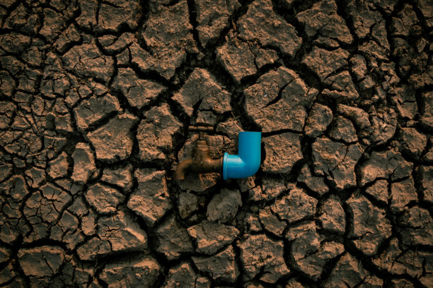 干渴的大地：一张描绘水资源短缺严峻现实的图片，一个古老、生锈的水龙头孤零零地立在龟裂、干涸的土地上，象征着干旱和环境危机。图片下载