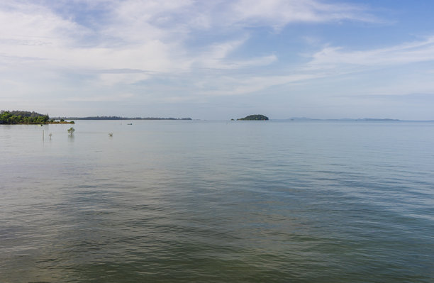 印度尼西亚勿里洞美丽的やや熱帯海灘風光。一望無際的平靜海面，遠處有著一座孤零零的小島，天空佈滿雲彩。海面平靜，直至海天相接之處。图片下载