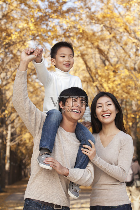 在公园里，男孩坐在他爸爸的肩膀上正版图片素材