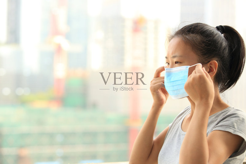 年轻女子戴着口罩在城市里正版图片素材