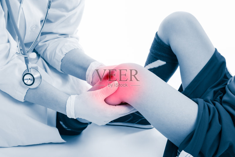 少年足球运动员膝盖疼痛，背景白色。医生性能正版图片素材