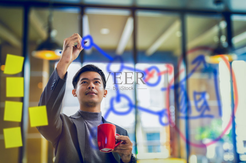 拿着咖啡杯在透明纸上写数据的商人正版图片素材