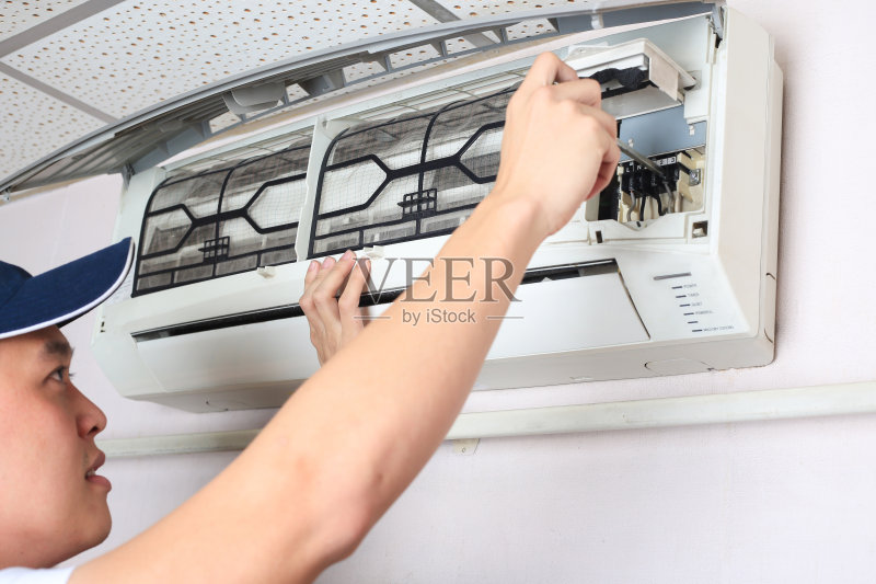 年轻人正在调整卧室的空调系统。正版图片素材