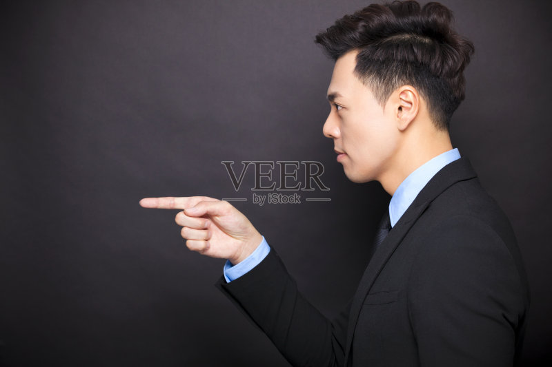 侧视愤怒的商人站在黑色背景前正版图片素材
