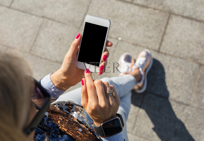 女性在户外使用智能手机正版图片素材