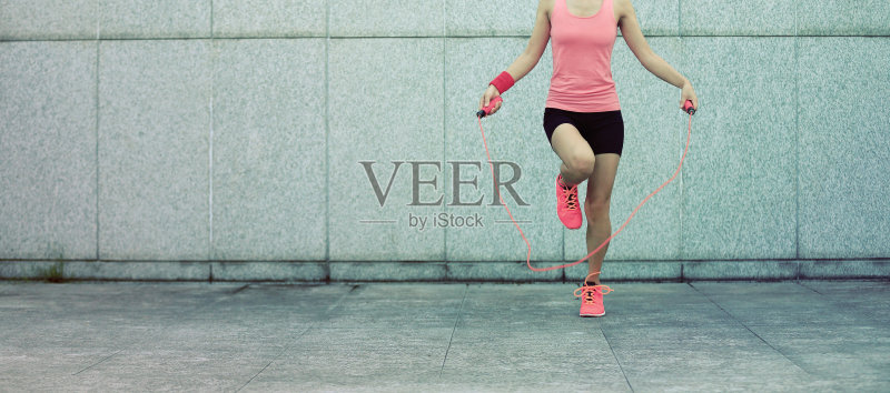 年轻的健身女子在城墙上跳绳正版图片素材