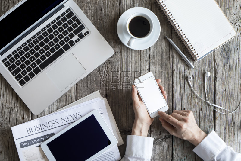 女人在工作台上使用手机正版图片素材