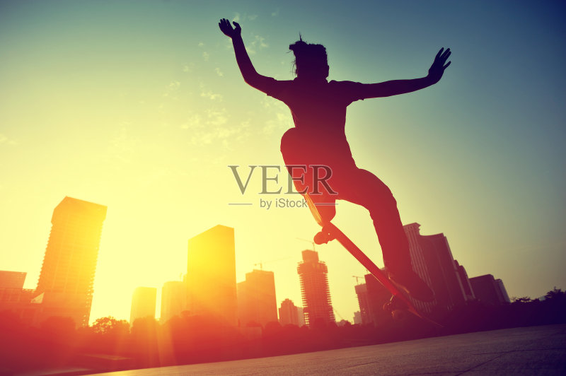 玩滑板的女人在日出时跳跃正版图片素材