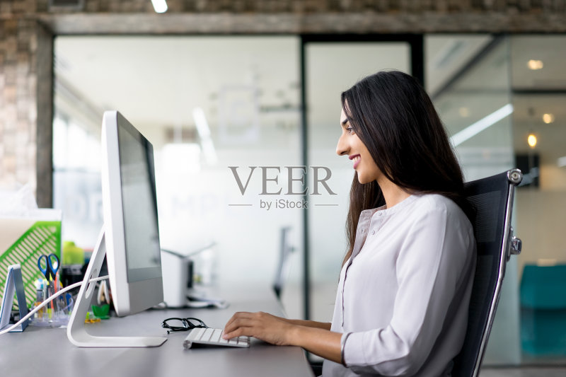 微笑着在电脑上打字的年轻女商人正版图片素材