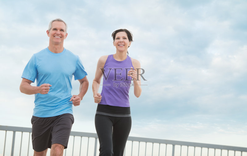 一对情侣在多云的天空下慢跑正版图片素材