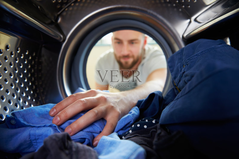 洗衣服的人把手伸进洗衣机里正版图片素材