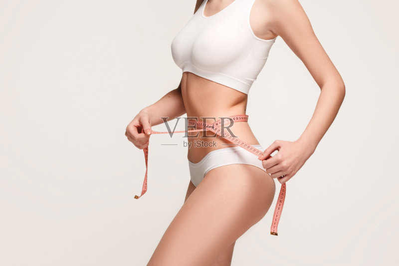 那个女孩在测量她的身体，白色的背景正版图片素材