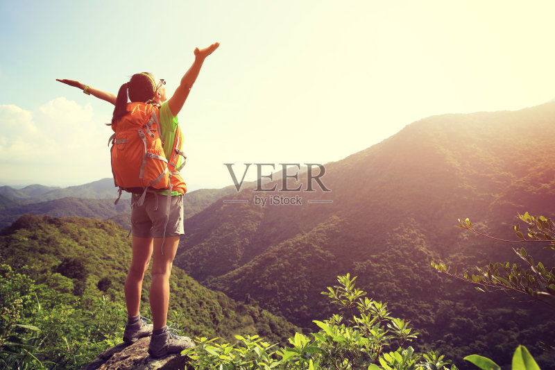 欢呼的女徒步者在山峰悬崖张开双臂正版图片素材